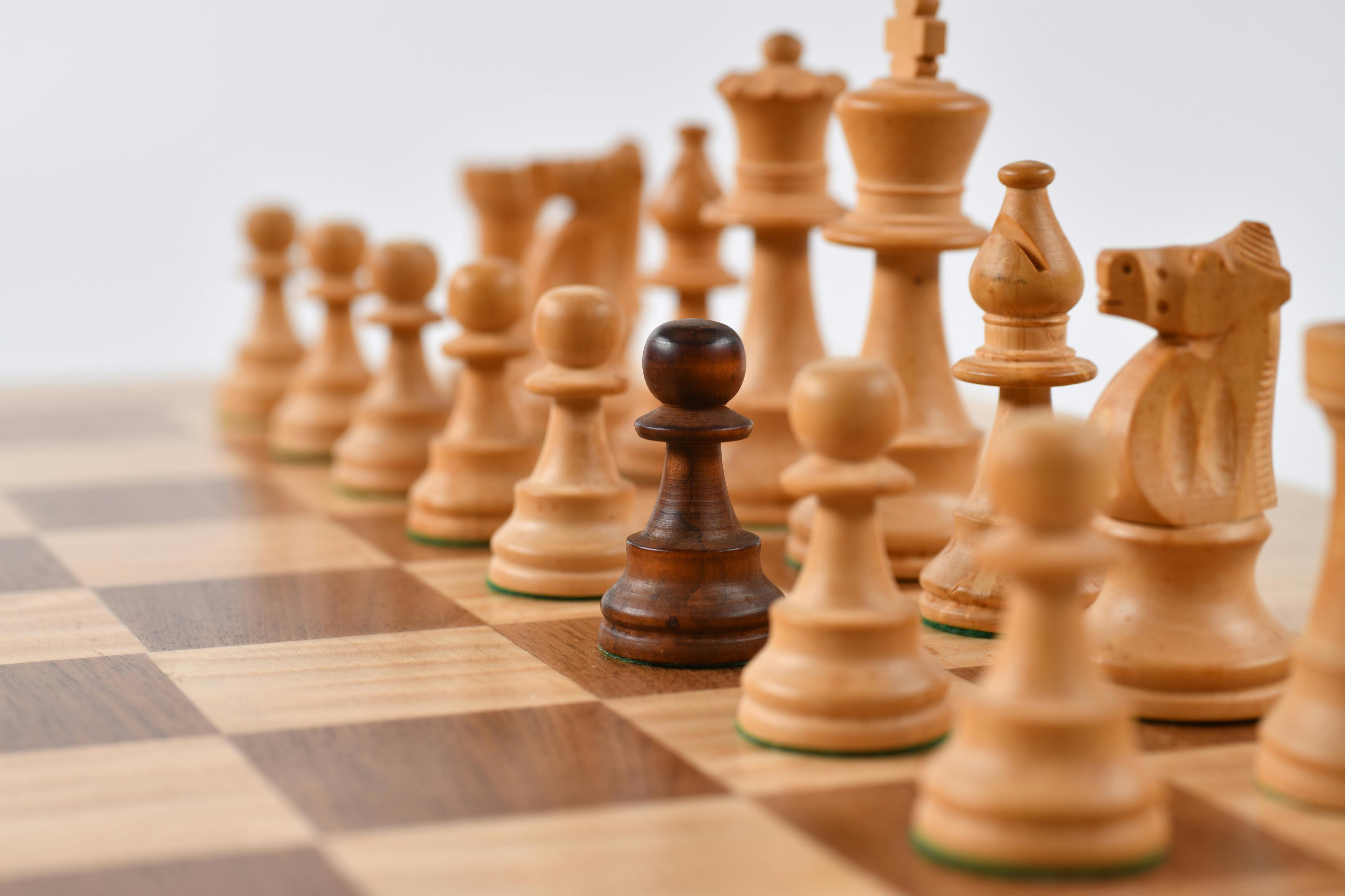 Wooden chess pieces lined up on a board