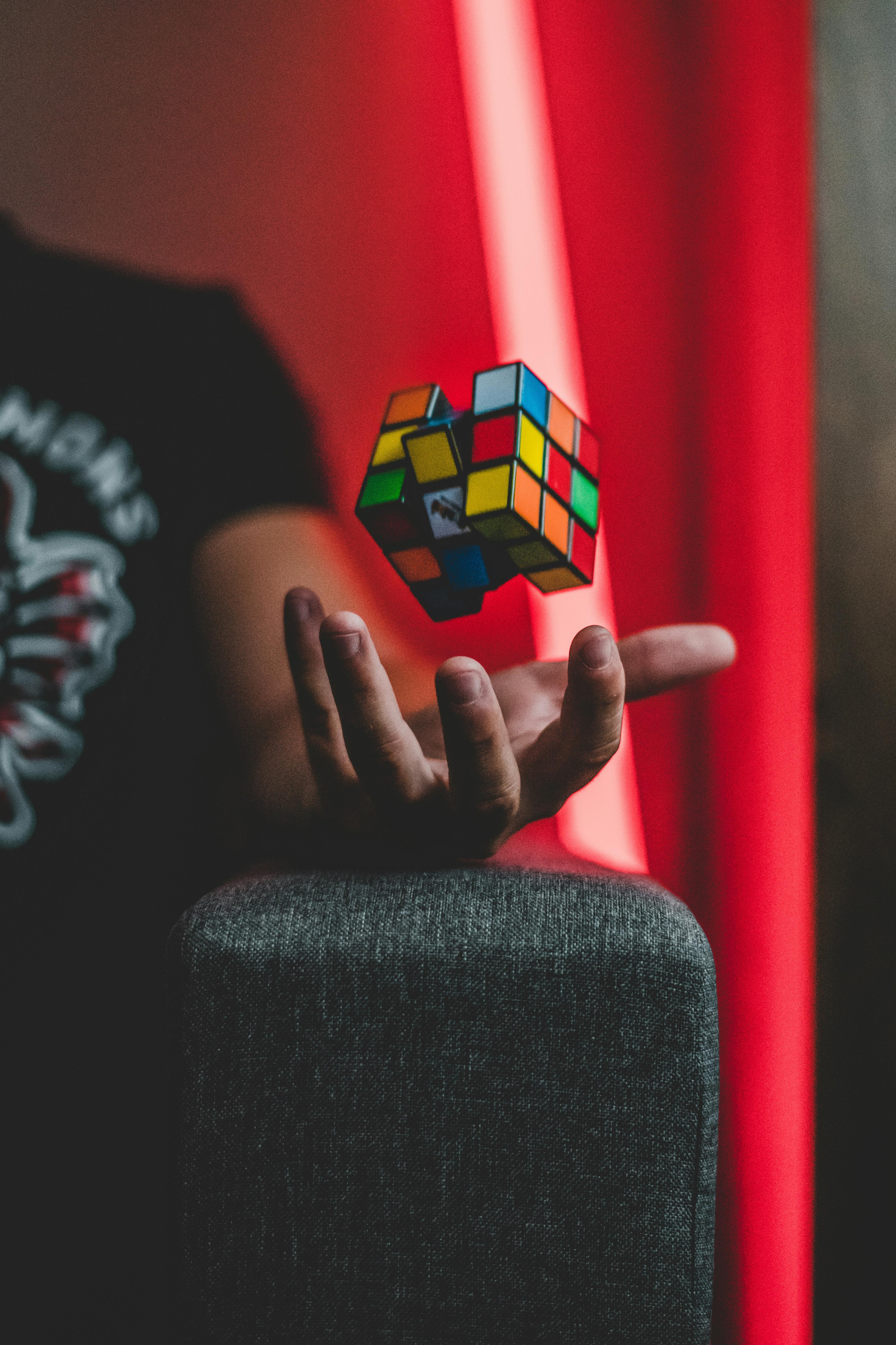 A hand tossing a Rubik's cube into the air