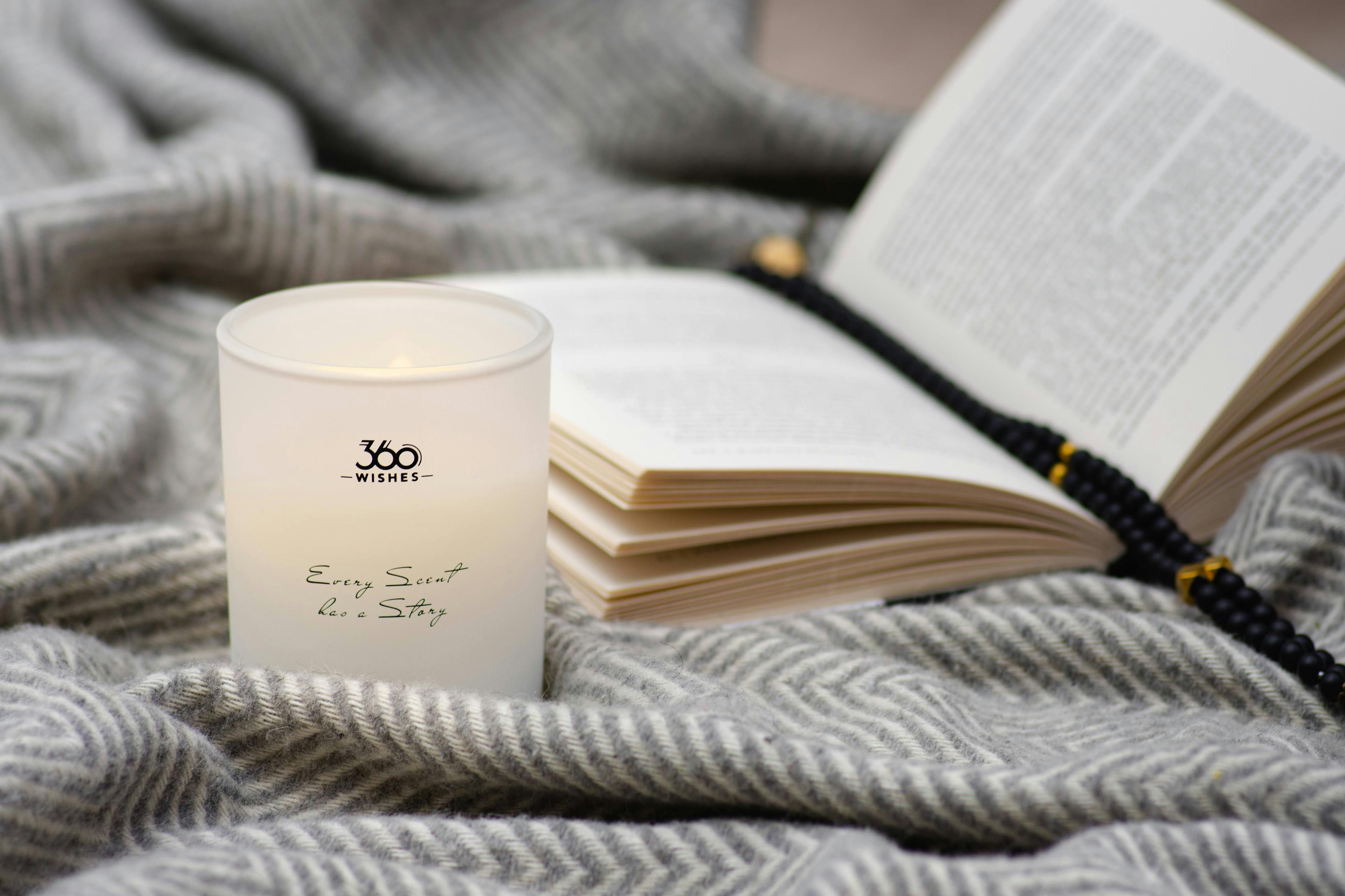 A candle and an open book on a knitted blanket