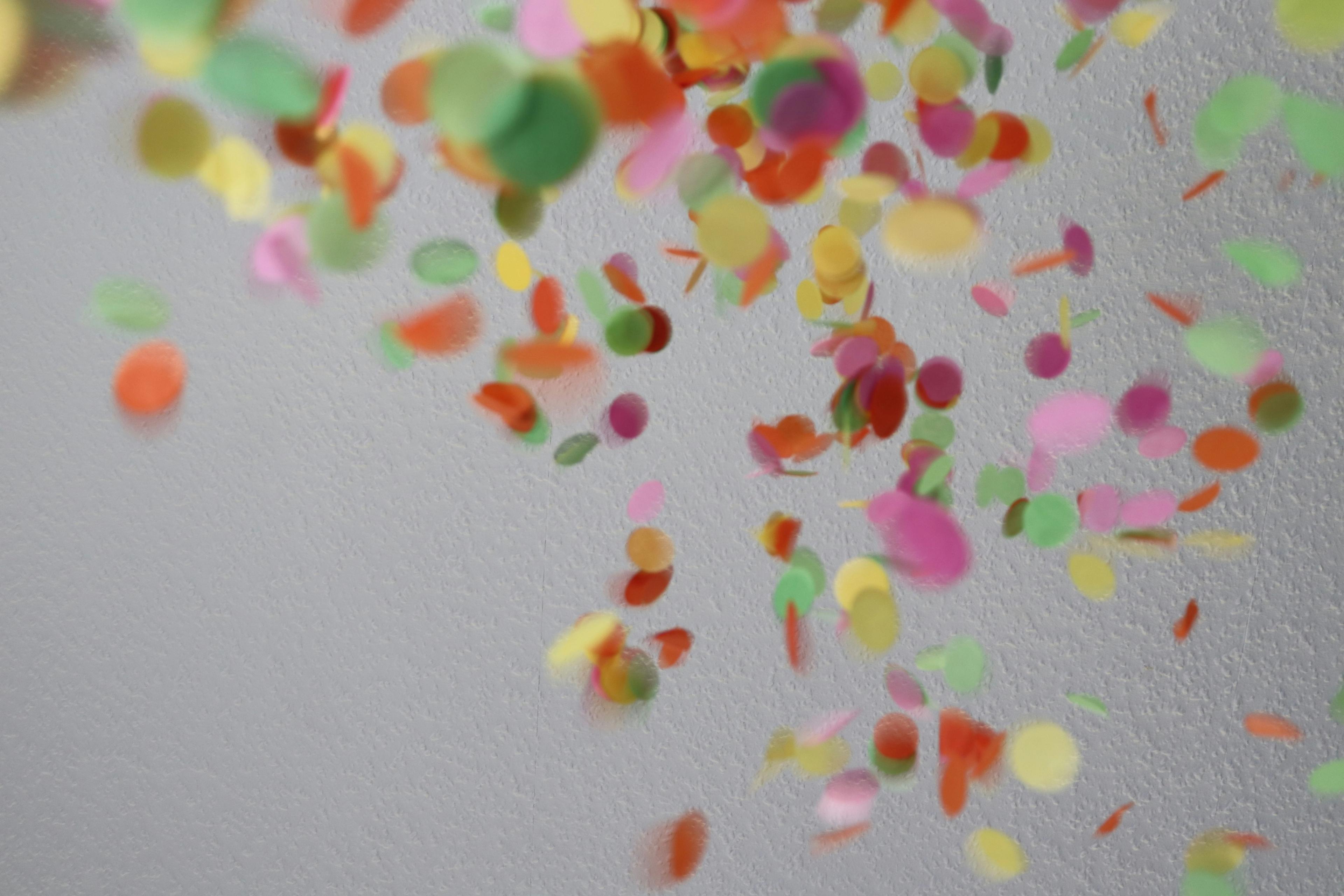 Colourful confetti falling against a white wall